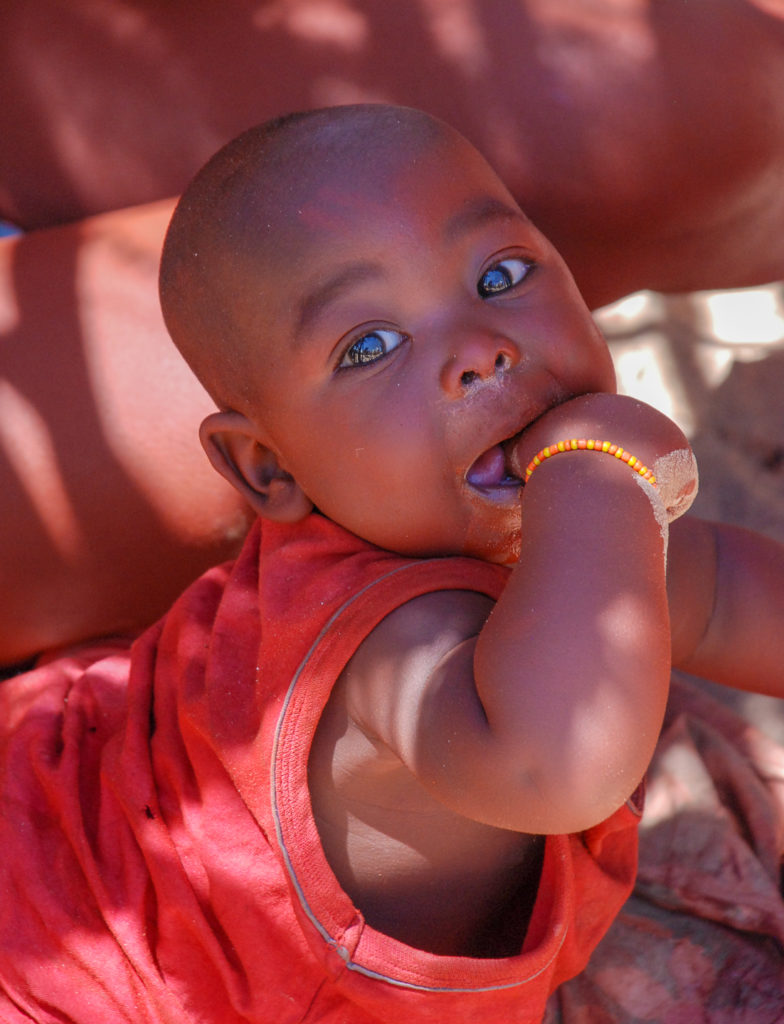 Him Baby mit roter Haut, rotem T-Shirt und blauen Augen