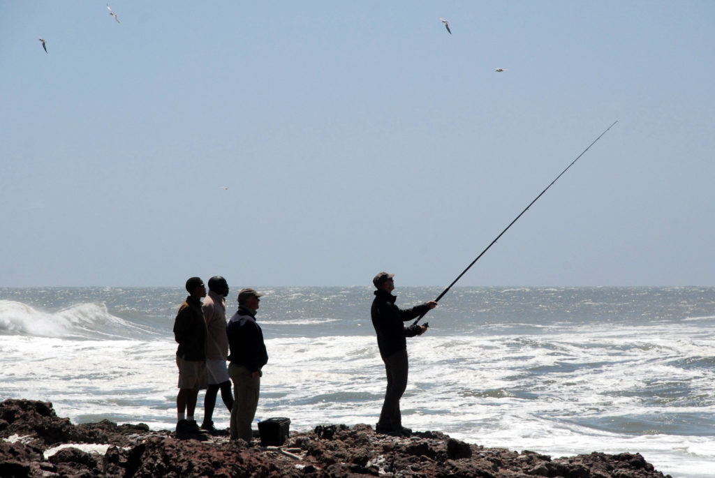 Angler im Gegenlicht an der wilden Meeresk&uuml;ste