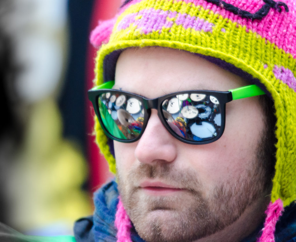 Kopfportrait eines Guggenmusikers mit greller Kappe und verspiegelter Sonnenbrille