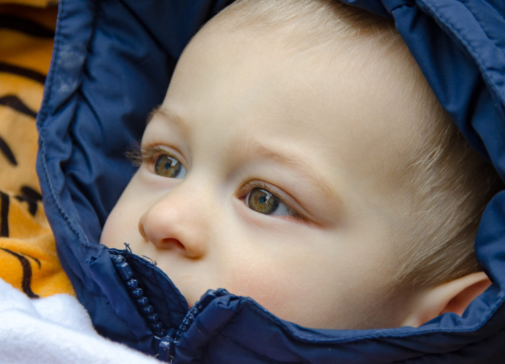 grosse Augen eines Kindes, warm eingepackt mit Kapuze