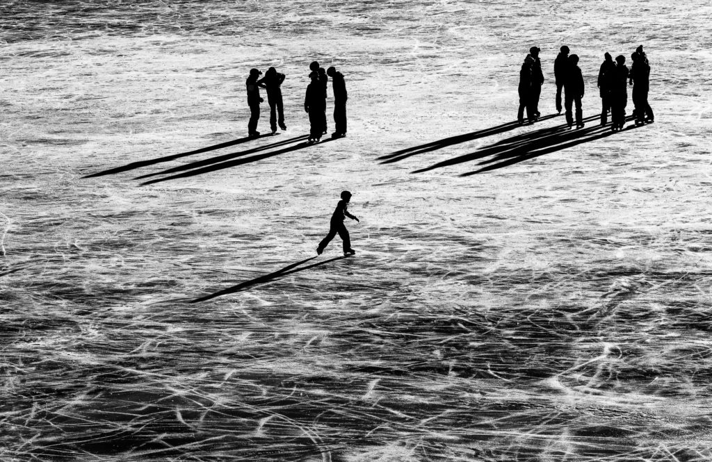 lange Schatten werfende Skater auf dem schwarzen Eis des Melchsee