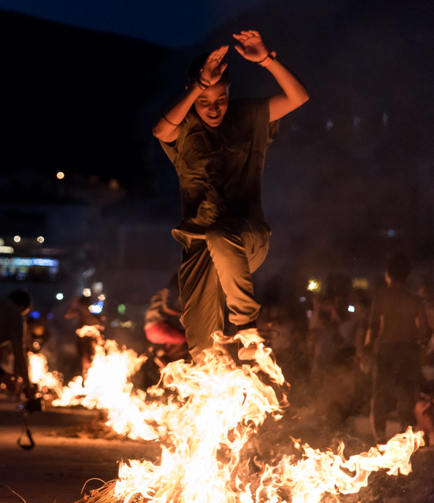 Junge der an einem nächtlichen Fest durch ein Feuer springt