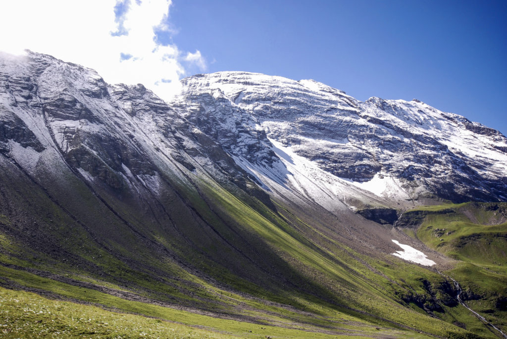 ein Hauch Schnee mit Schnee überzuckerte Berggipfel vor saftig-grünen Wiesen