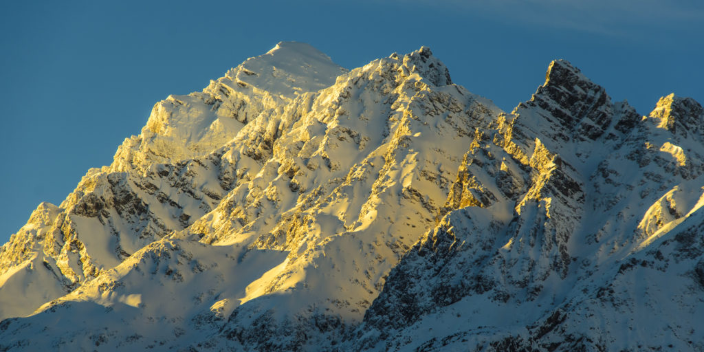in den letzten Sonnenstrahlen glühende Berggipfel im Neuschnee