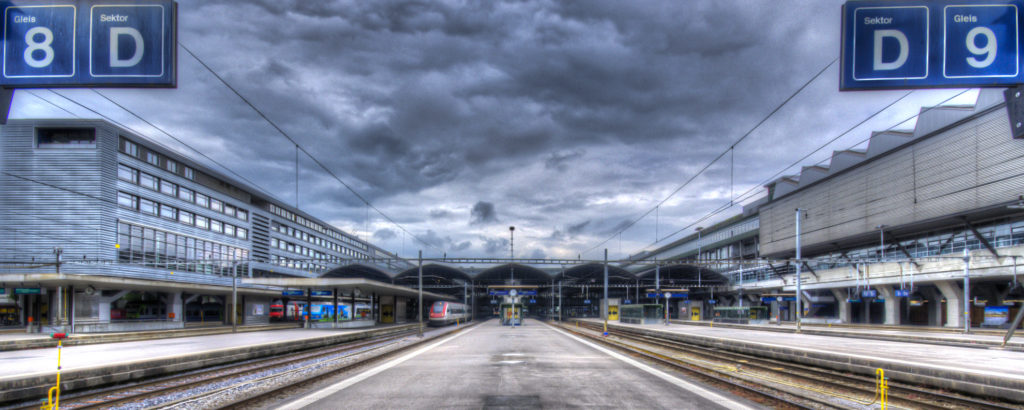 Zentralperspektive der Geleise 8 und 9 des Bahnhofs Luzern mit dunklen Gewitterwolken