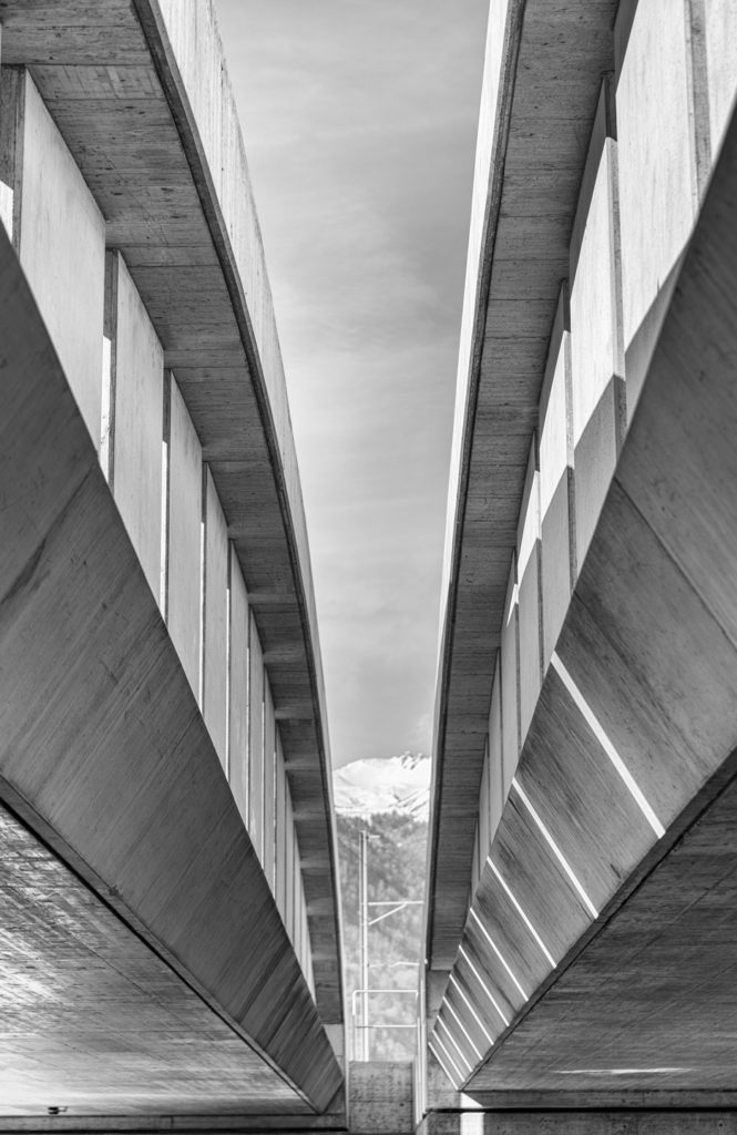 massive Eisenbahnbrücke aus Beton in Schwarz-Weiss aus ungewohnter Perspektive