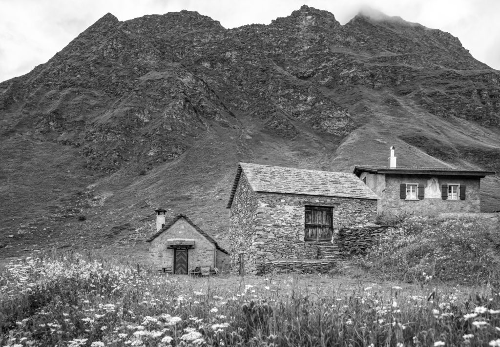 Alte Steinh&auml;user vor grauer Bergkulisse in Schwarz-Weiss