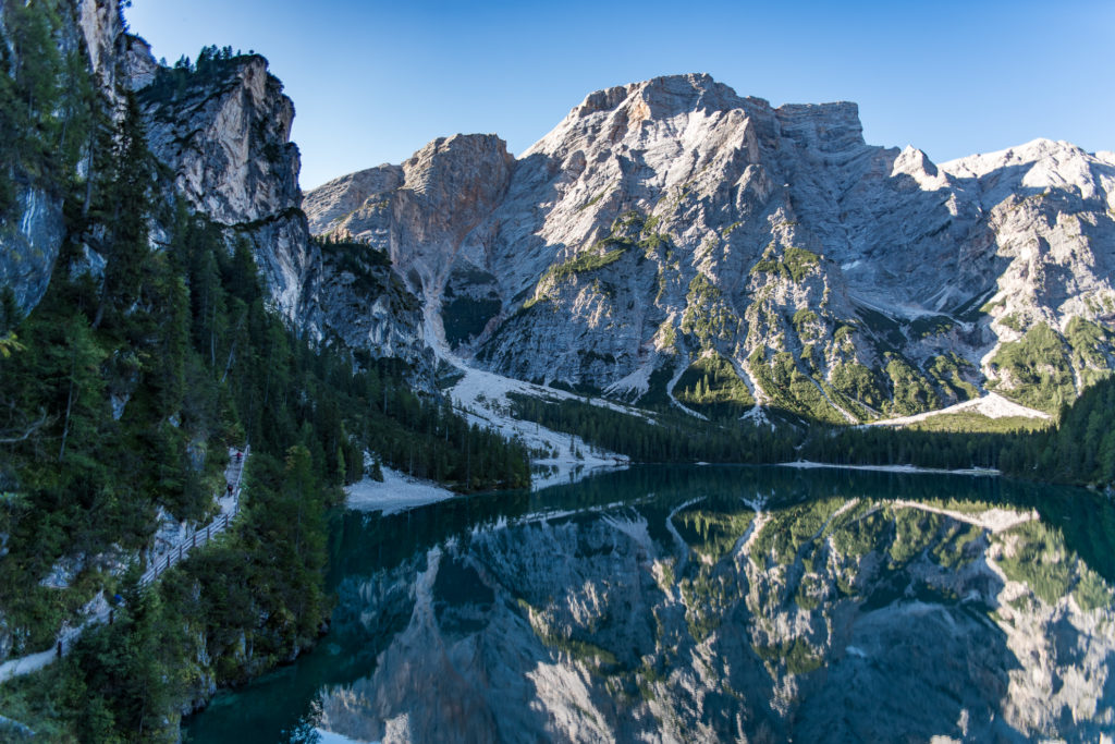 Die von den ersten Sonnenstrahlen beleuchteten Berggipfel spiegeln sich im Pragser Wildsee