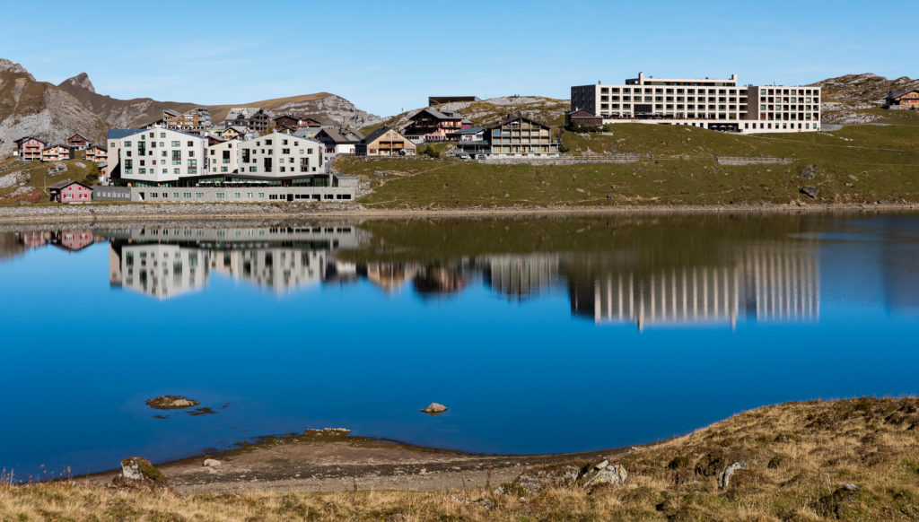 Frutt-Lodge und Frutt-Spa spiegeln sich im ruhigen, tiefblauen Wasser des Melchsees