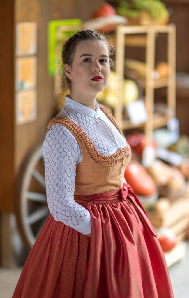Portrait Fotografie, Available Light: klassisches Dirndl im Brustportrait seitlich vor K&uuml;rbis-Kulisse