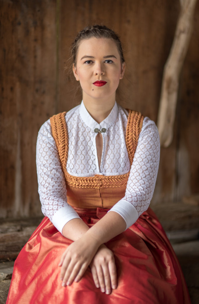 Portrait Fotografie, Available Light: klassisches Dirndl im Brustportrait frontal vor Holzwand