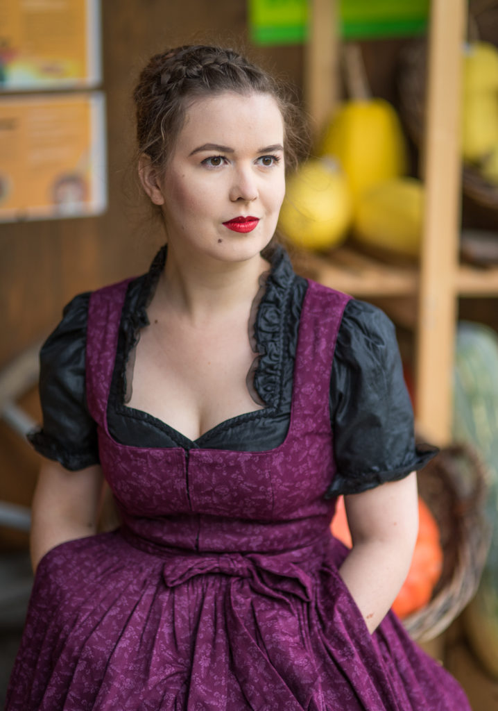 Portrait Fotografie, Available Light: klassisches, dunkelrotes Dirndl im Halbportrait frontal