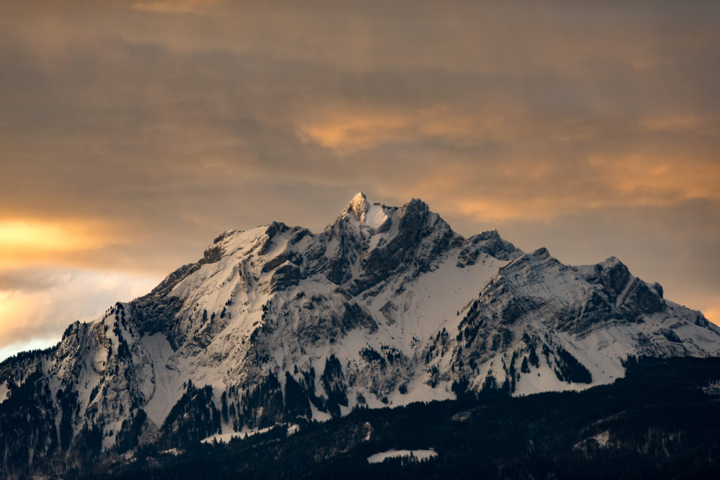 verschneiter Berggipfel mit ersten Sonnenstrahlen und roten Wolken
