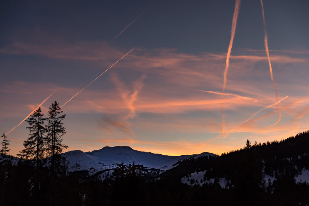 roter Himmel w&auml;hrend der blauen Stunde, schneebedeckte Berge, Kondensationsstreifen
