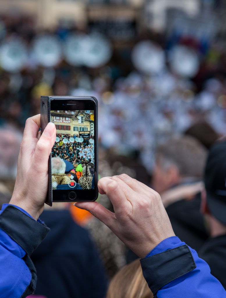 Luzerner Fasnacht, Auftritt einer Guggenmusik, durch das Handy beobachtet