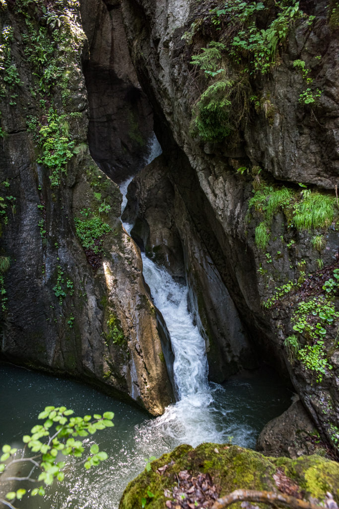 Flusslandschaft im Muotathal, tief im Fels eingegrabener Wasserfall mit Streiflicht der Sonne