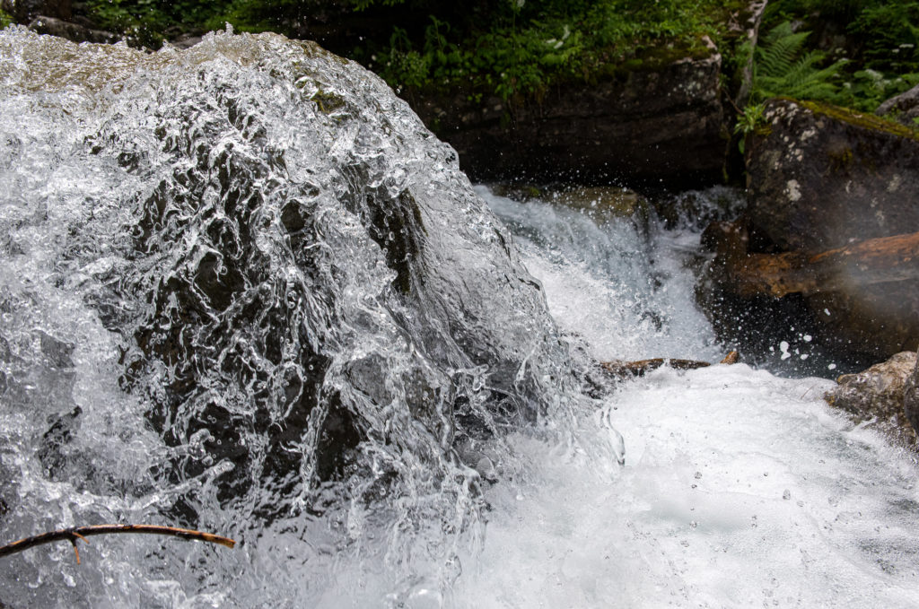Wasserskulptur tobendes Wasser über eine Steinschwelle