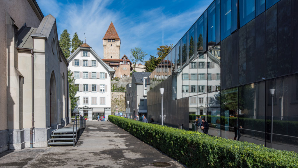 Kirche, alte Geb&auml;ude, Stadtmauer und Turm die sich in einer Glasfassade spiegeln