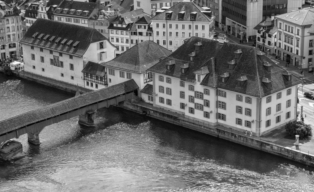 Drohnenperspektive eines alten Gebäudekomplexes mit Holzbrücke in Schwarz Weiss