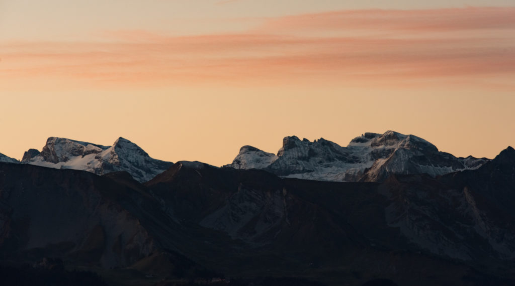 leicht verschneite Berggipfel im fr&uuml;hen Morgenlicht mit rotem Himmel