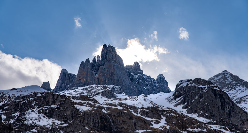 verschneite Felszacken im Gegenlicht mit Wolkenhimmel