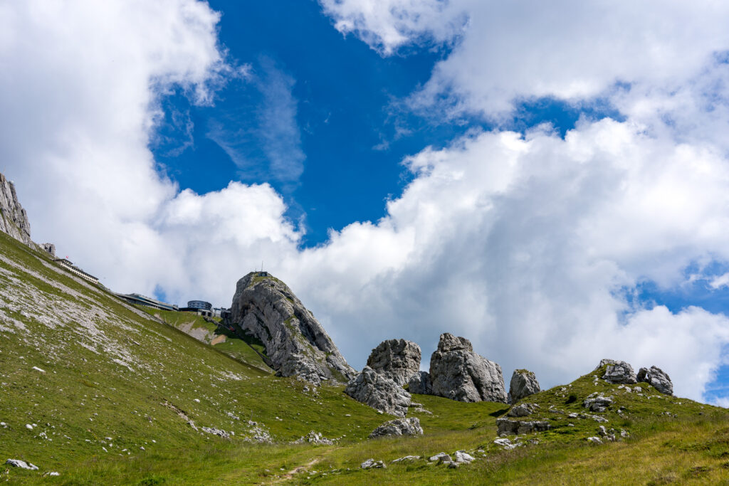 Felsblöcke und Gipfelrestaurant Pilatus mit weissen Quellwolken
