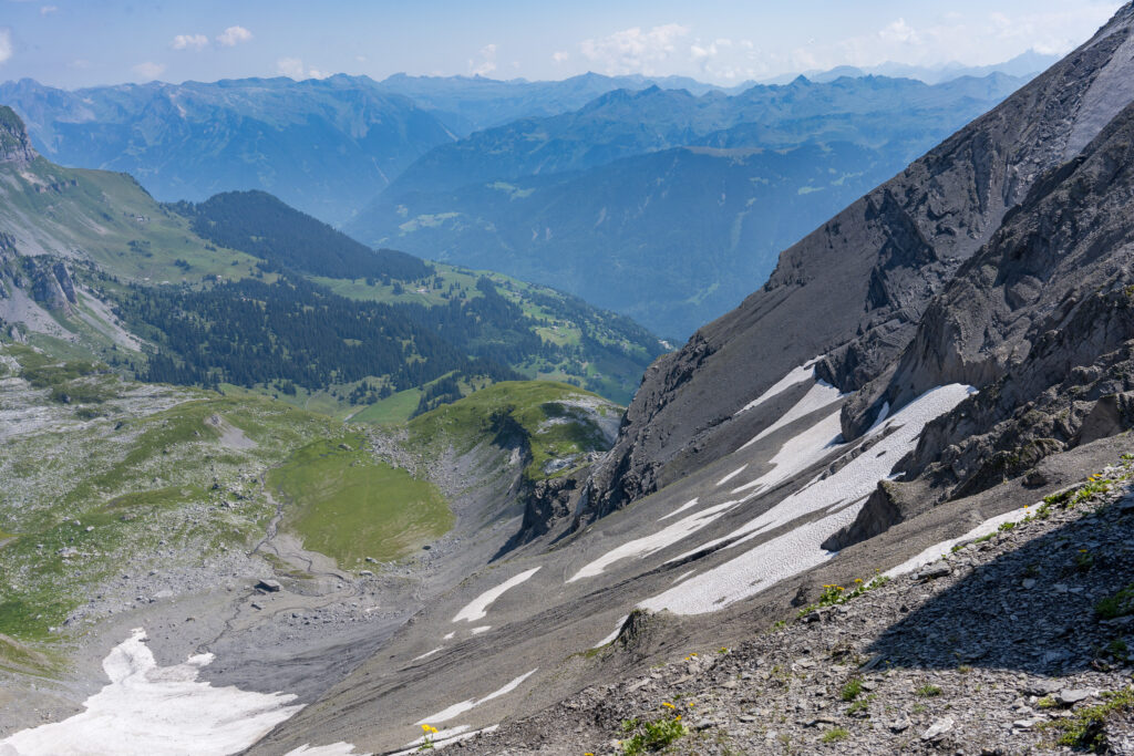 Ausblick &uuml;ber steile Ger&ouml;llfelder mit Schneeresten, im Hintergrund die Glarner Alpen