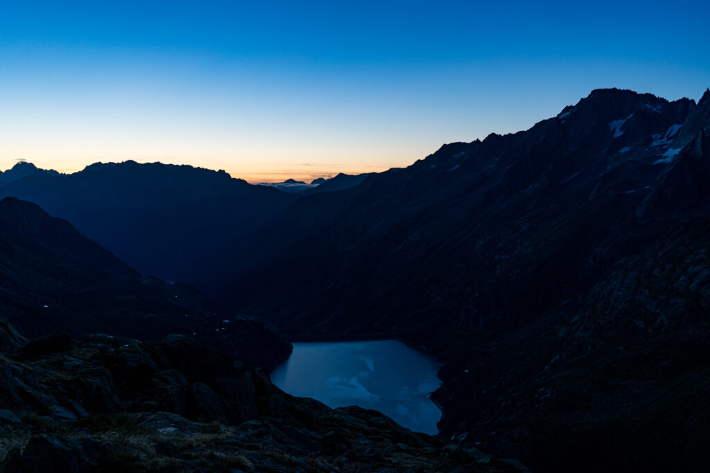 Morgendämmerung mit Tiefblick auf dunklen Bergsee