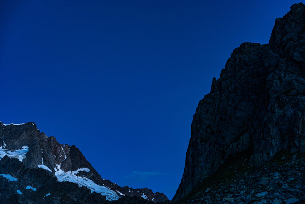 dunkle Berggipfel kurz vor Sonnenaufgang mit leuchtendem Gletschereis