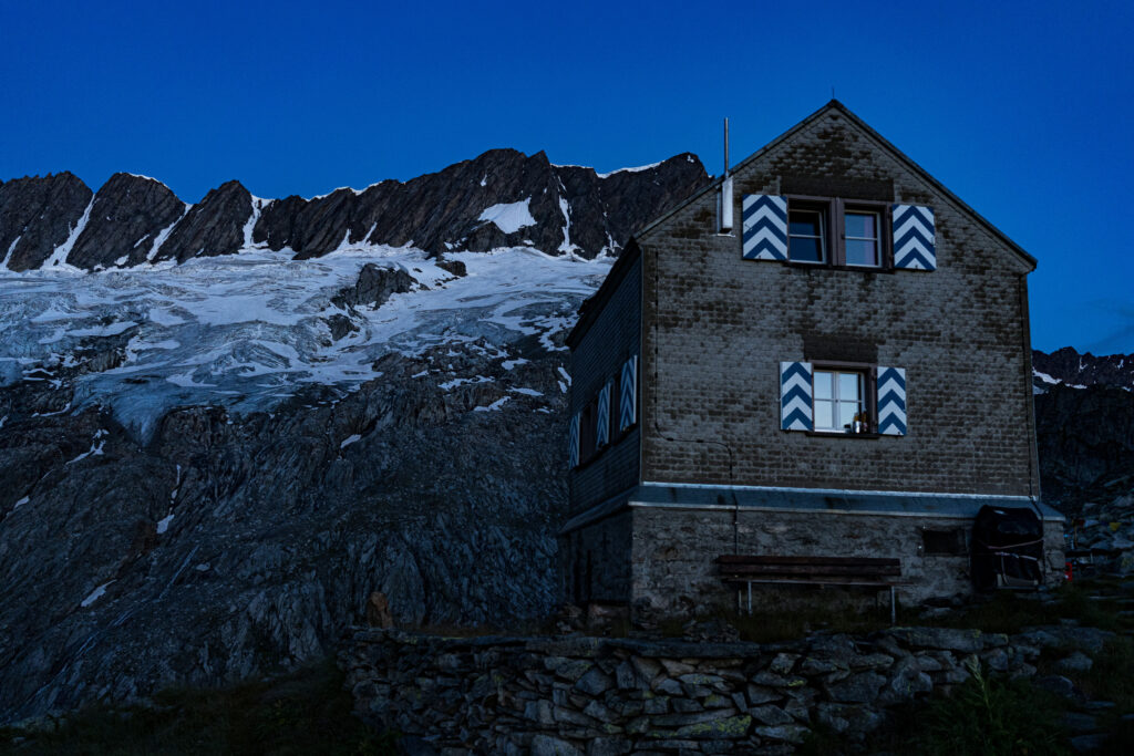 Berghütte vor Felsbergen und Gletschern im Morgengrauen