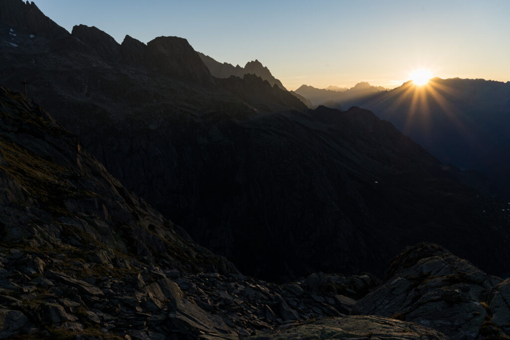 erstes Sonnenlicht bricht durch die Berggipfel im Gegenlicht